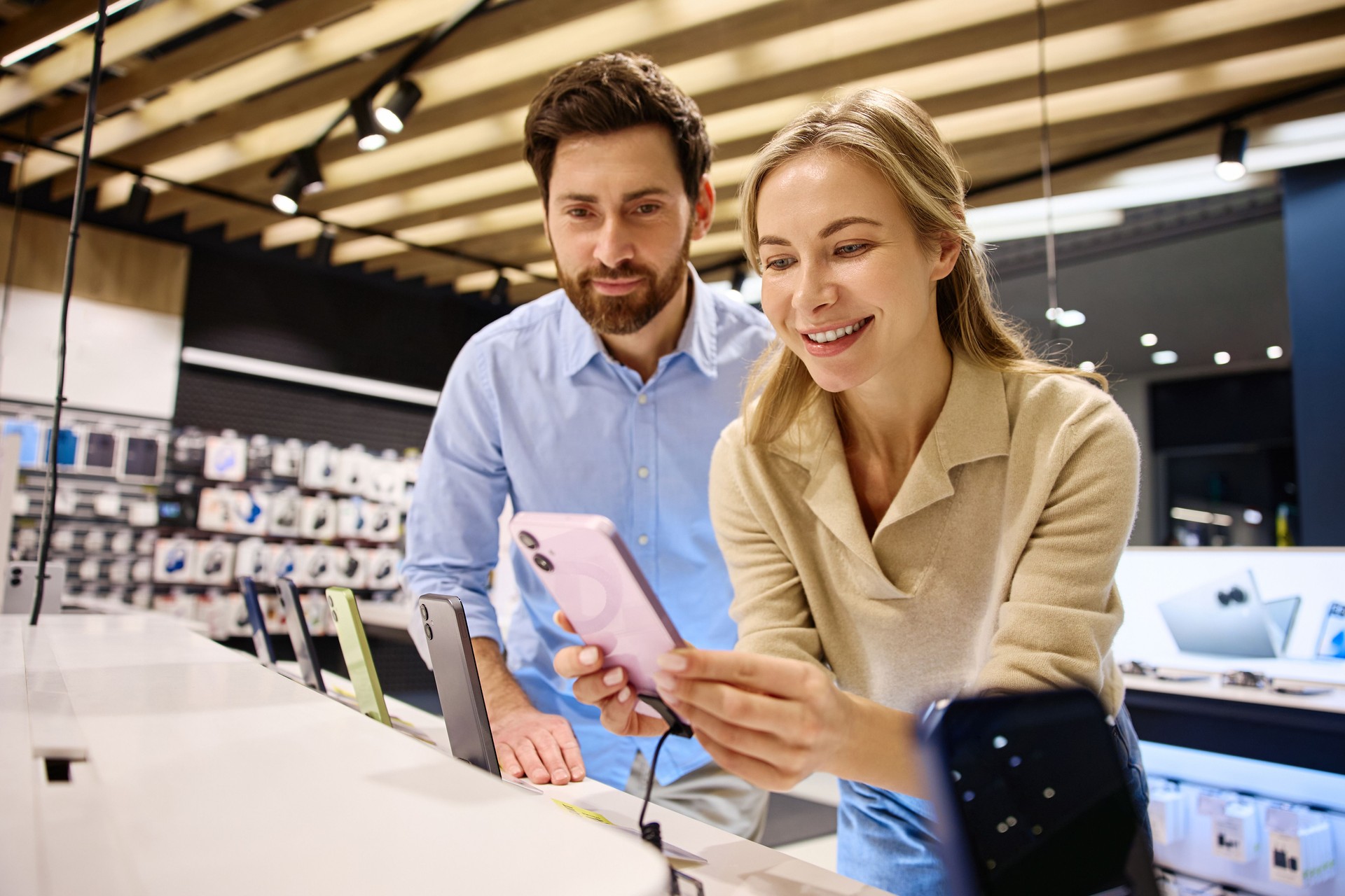 A Couple Enthusiastically Exploring the Latest Models of Smartphones in a Local Electronics Store